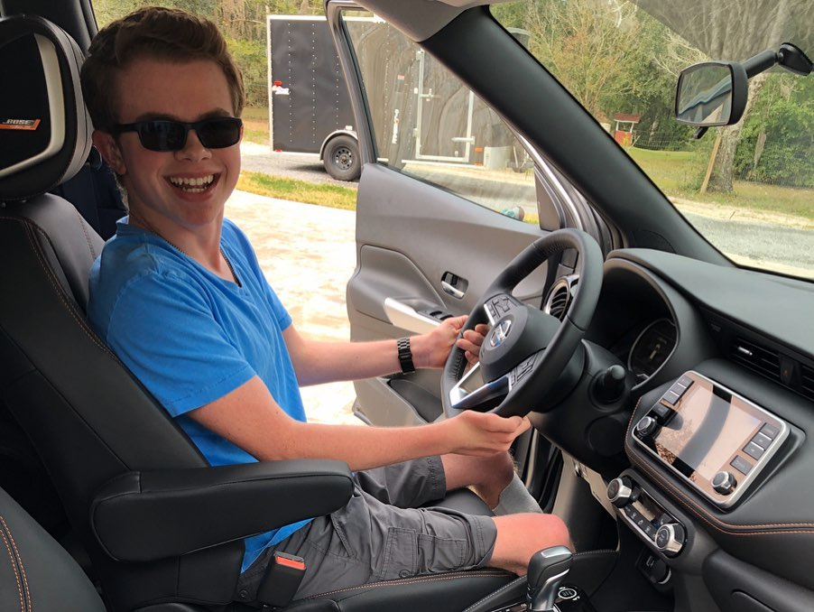 Ryleigh Newman smiling in the driver's seat of his car.