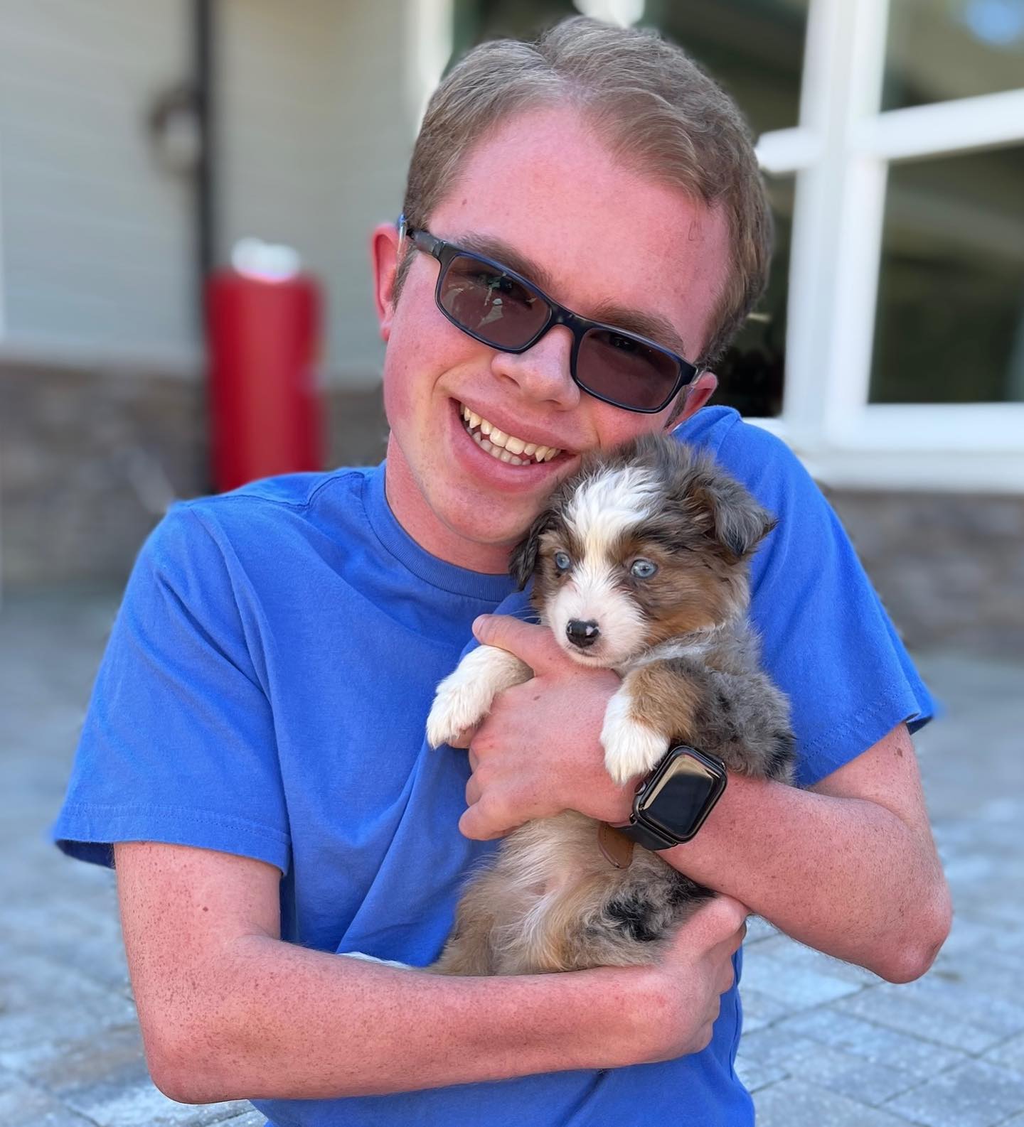 Ryleigh Newman holding an Australian Shepherd puppy on the family ranch.