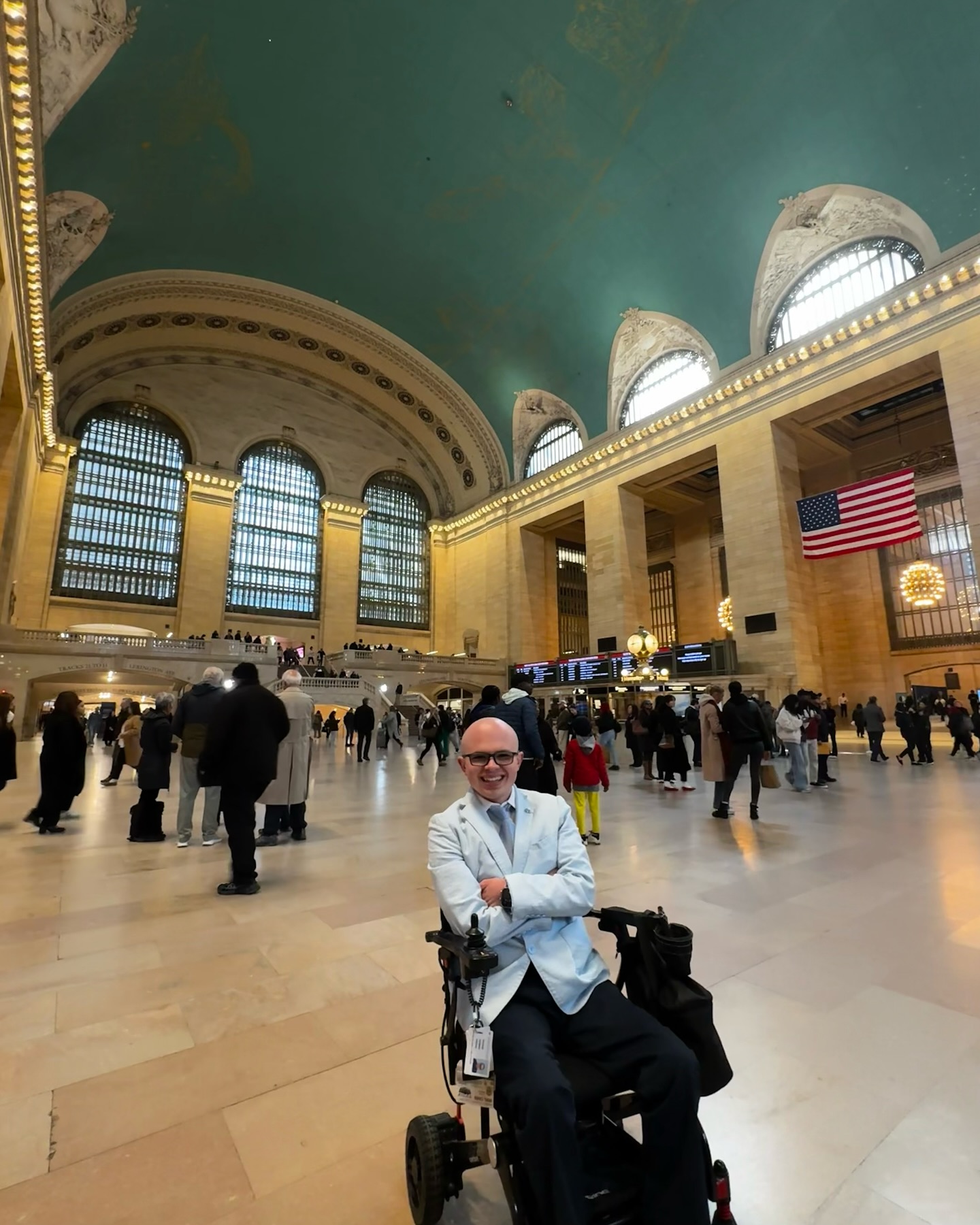 Ryleigh Newman in the main concourse of Grand Central Terminal under the green and gold astronomical ceiling, a large American flag hanging beside the windows.